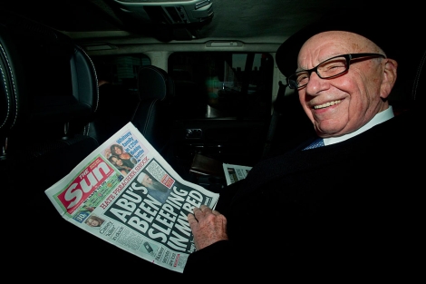 Murdoch lee un ejemplar de 'The Sun' al salir de su casa en Londres este viernes. | Efe
