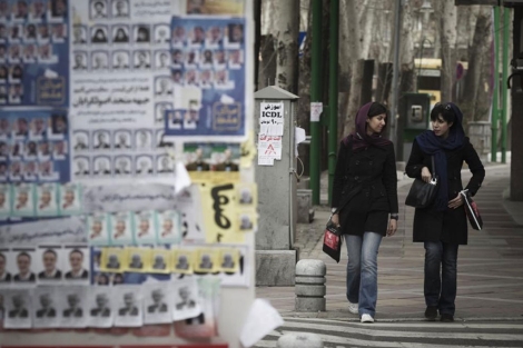 Dos mujeres iranes junto a carteles electorales en Teheran. | Reuters