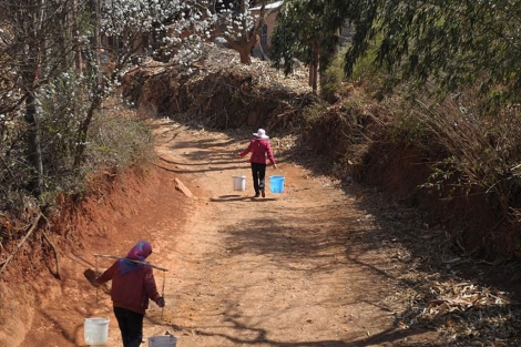 Dos mujeres chinas cargan agua de camino a su poblado. | Efe