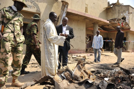 Un sacerdote junto a la polica tras un atentado de Boko Haram en una iglesia de Madalla. | Reuters