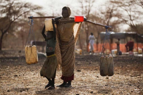 Una mujer transporta agua con su hija en el campo de refugiados de Sudn.| Reuters