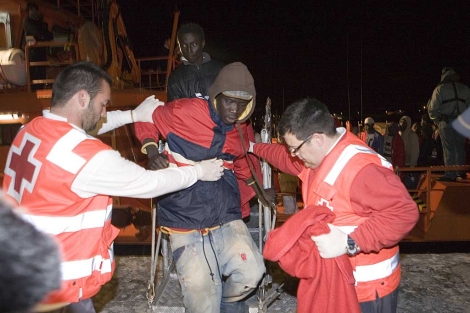 Miembros de la Cruz Roja ayudan a desembarcar a un inmigrante. | Efe