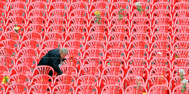 Una mujer, dentro del grupo de sillas vacías como homenaje. | Afp