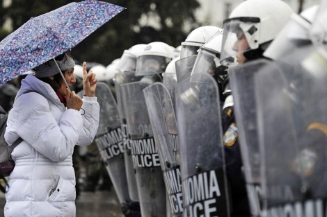 Una ciudadana, ante policías en una huelga general en Atenas en febrero. | Afp