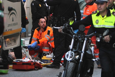 Un sanitario atiende al conductor de la moto, junto a policas locales. | C. Mrquez