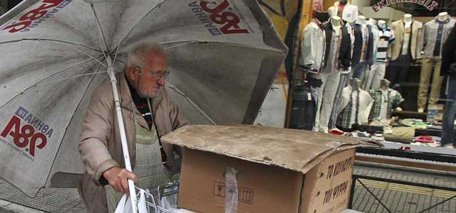 Un vendedor callejero empuja su carrito bajo la lluvia en Atenas este viernes. | Efe