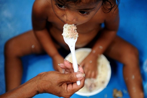 Una madre alimenta a su hija en Filipinas. | Afp