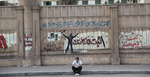 Una joven sentado frente a una pared con pintadas en el barrio de Abbasiya de El Cairo. | F. Carrin