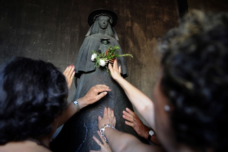 Varias mujeres ofertan flores a una imagen de la Virgen del Rocío, ayer, en la aldea. | Afp