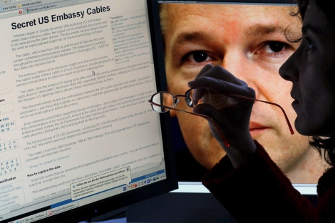 Una mujer analiza las filtraciones junto a una foto de Assange. | Afp