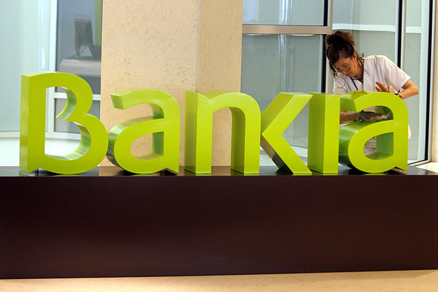 Una operaria limpia el logo de Bankia en la sede central de Bancaja, en Valencia. | Efe