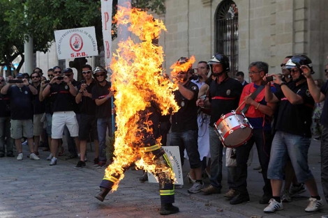 El bombero, ataviado con traje ignfugo, corre envuelto en llamas. | E. Lobato