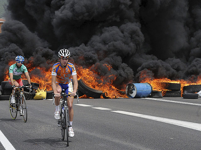 Dos ciclistas, ante la barricada en llamas en una carretera que une León y Asturias, a la altura del municipio de La Robla. | Efe