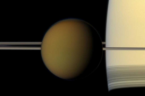 Titán (i) durante su órbita alrededor de Saturno. | NASA