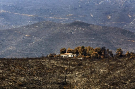 Vista de una casa rodeada de monte quemado en Macastre (Valencia). | Efe