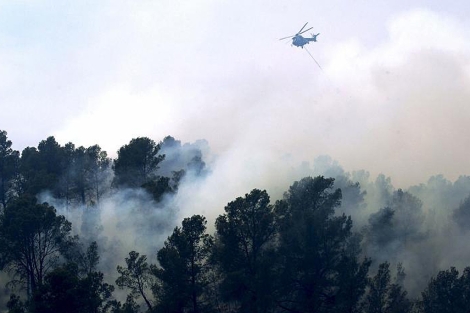Un helicptero vuela sobre el fuego durante los trabajos de extincin del incendio de Liria. | Efe