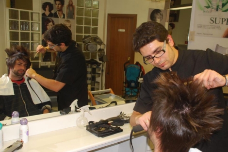 Un peluquero atiende a un cliente en una peluquera de Valladolid.