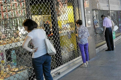 Unas personas miran los escaparates de unas tiendas cerradas | E. M