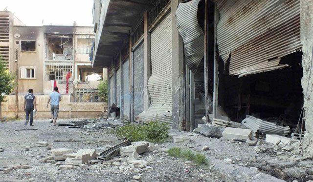 Dos hombres caminan por una calle de Homs, donde se ven las consecuencias de los ataques.| Reuters