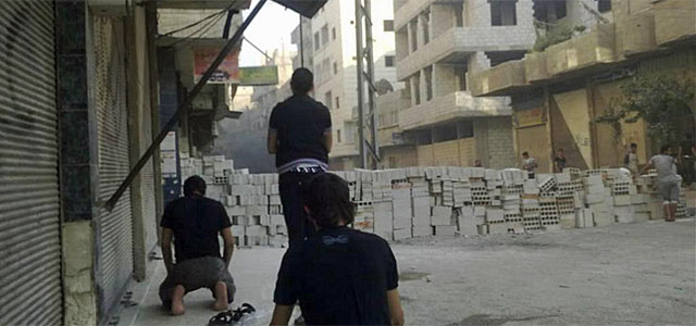 Tres opositores rezan detrs de una improvisada barricada en Al Tadamun.| Afp