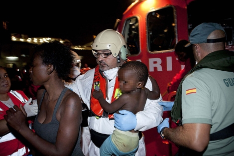 Un miembro de Salvamento Martimo, con un nio en brazos en el puerto de Motril. | Efe