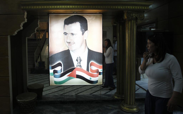 Una mujer camina cerca de un retrato del presidente sirio Asad, en Damasco. | Reuters