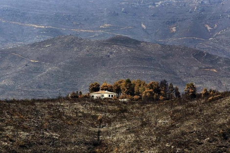 Vista de una casa rodeada de monte quemado en Macastre, Valencia. | Efe