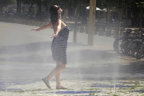 Una turista se refresca para mitigar los efectos del calor. | Efe