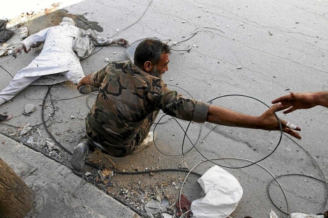 Un miembro del ejrcito arrastra un cadver en Alepo.