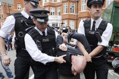 La polica britnica sujeta a otro de los detenidos frente a la embajada ecuatoriana. | Efe