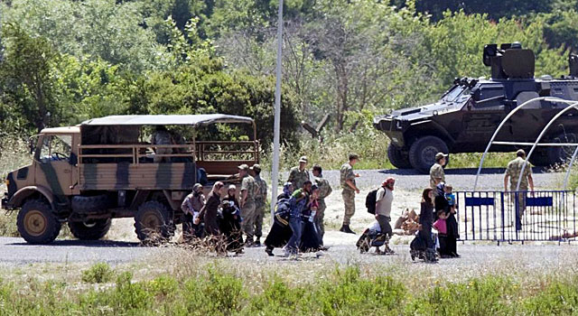 Soldados turcos supervisan el paso de varios refugiados sirios. | Ap