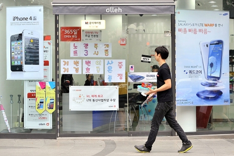 Un hombre pasa por delante de una tienda con carteles publicitarios del iPhone (izda) y el Galaxy (dcha), en Seul. | AFP
