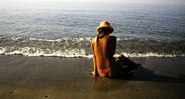 Una mujer se relaja en una playa. | El Mundo