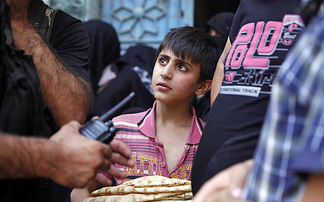 Un chico mira a milicianos rebeldes, mientras sostiene el pan, en Alepo. | Reuters | MS IMGENES 