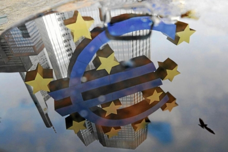 Reflejo en un charco del símbolo del euro frente a la sede del BCE. | Efe