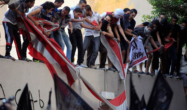 Manifestantes egipcios sobre el muro de la embajada norteamericana en El Cairo. | Reuters