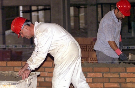 Dos obreros colocan ladrillos en la construcción de un edificio. | Ángel Casaña