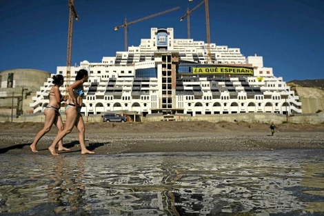 Dos baistas pasean delante del hotel a medio construir. | Reuters