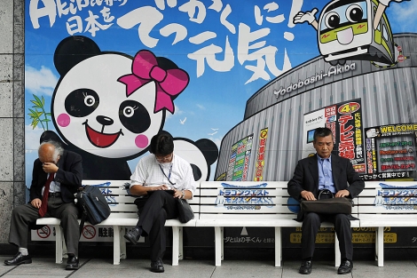 Tres japoneses sentados en un banco en Tokio. | Reuters