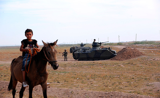 Un nio monta a caballo en Akakale. Detrs suyo, militares turcos.| Afp