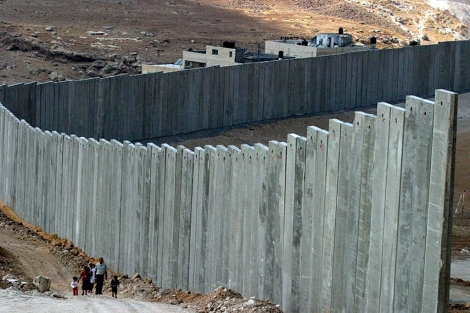 Palestinos caminan junto al Muro que construye Israel en Cisjordania, en Abu Dis, al este de Jerusalén.| Efe