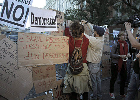 Varias personas cubren con carteles la valla policial en Neptuno. | Kiko Huesca / Efe