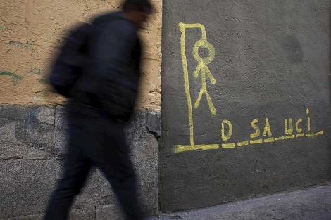 Un hombre camina junto a un cartel que recrea el juego del ahorcado. | Reuters