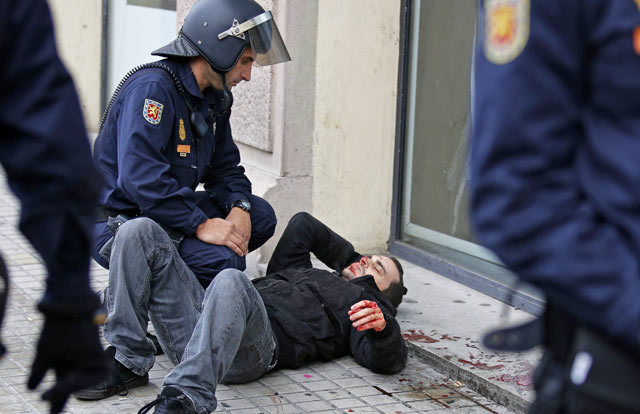 Un agente del Cuerpo Nacional de Polica atiende a un joven herido en uno de los enfrentamientos. | Efe