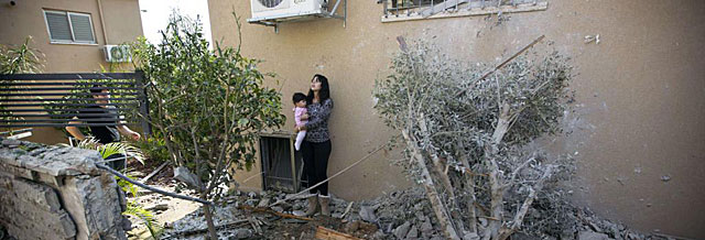 Una israel contempla con su beb en brazos los destrozos producidos en su jardn por un misil palestino. | Afp