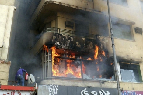 Un hombre trata de apagar el fuego declarado en la sede de la emisora. | Efe