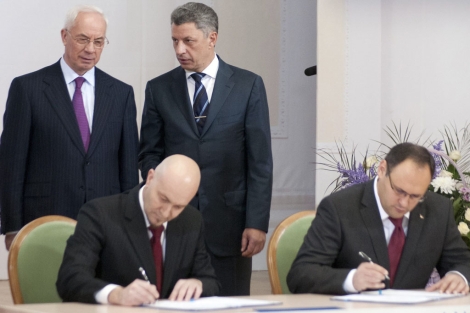 El primer ministro de Ucrania, Mykola Azarov (de pie a la izq.) mientras el falso representante, Jordi Sardà Bonvehi (sentado, izq.), firmaba el acuerdo. | Reuters