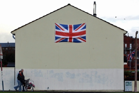 Una familia pasa junto a una casa con la bandera británica en Belfast. | Foto: Reuters