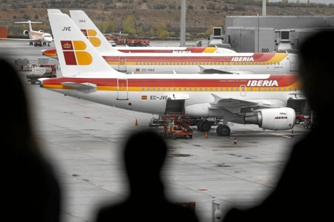 Pasajeros frente a aviones de Iberia en la T4. | Reuters