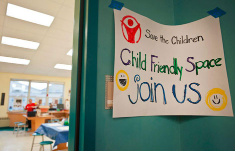 Un cartel invita a los niños a jugaren una escuela en Newtown. | Facebook/Save the Children